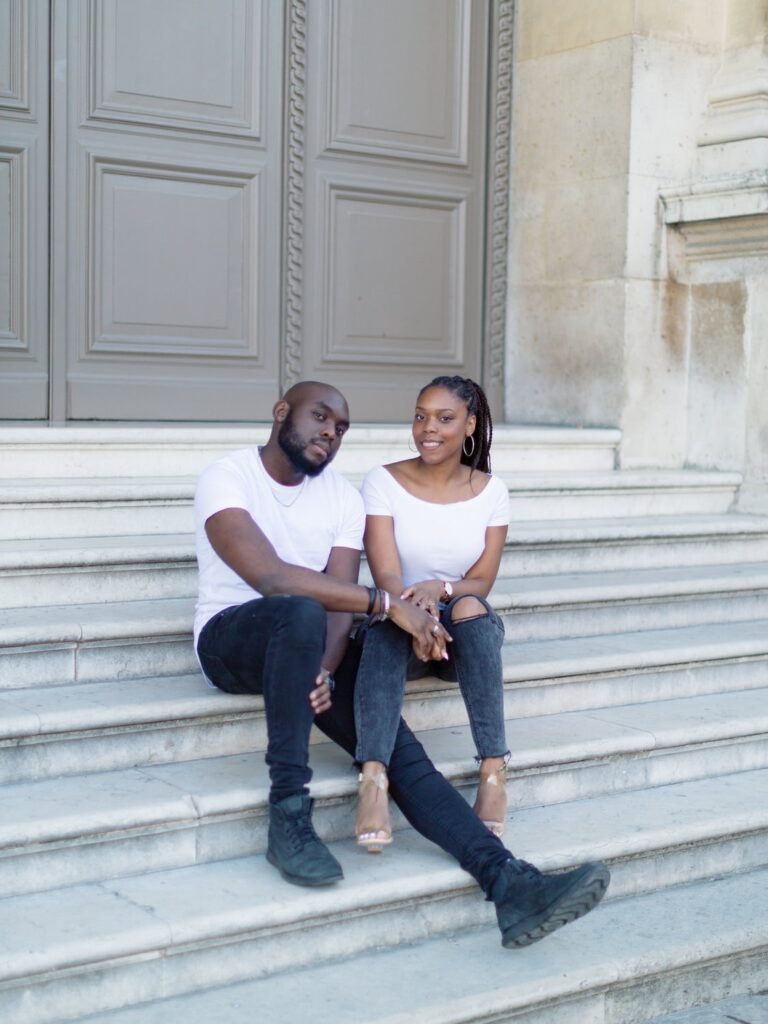 couple sit on the stair of the courtside of the louvres museum during Engagement session Louvres Paris