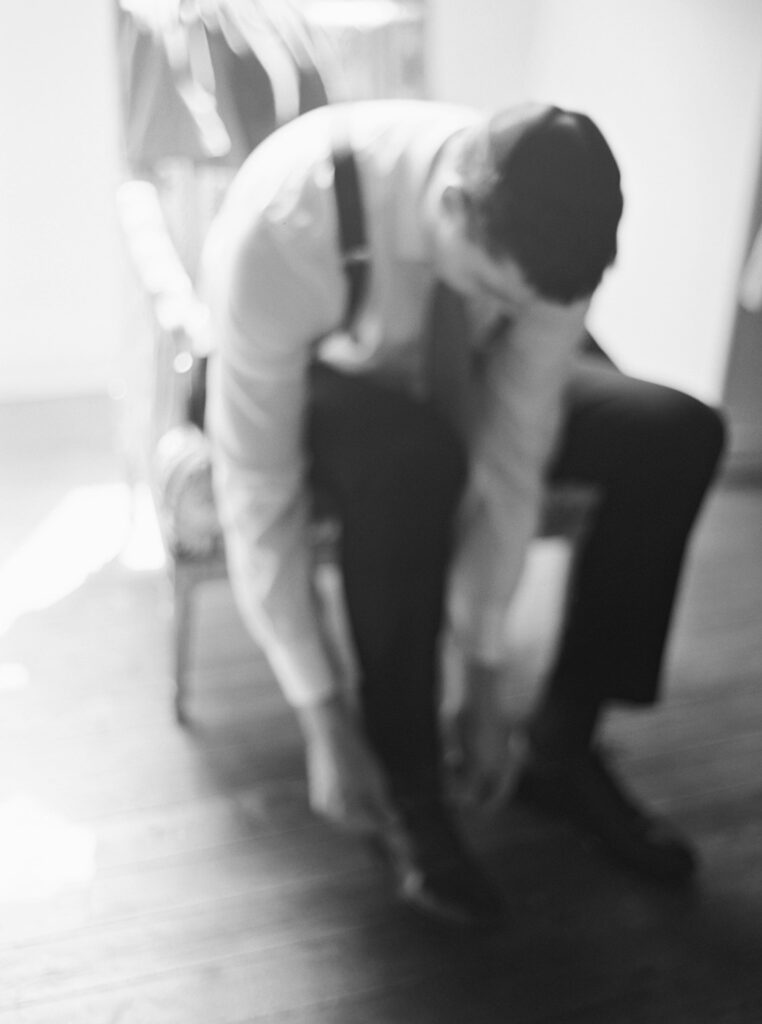 photo noir et blanc d'un marié qui arrange sa chaussure